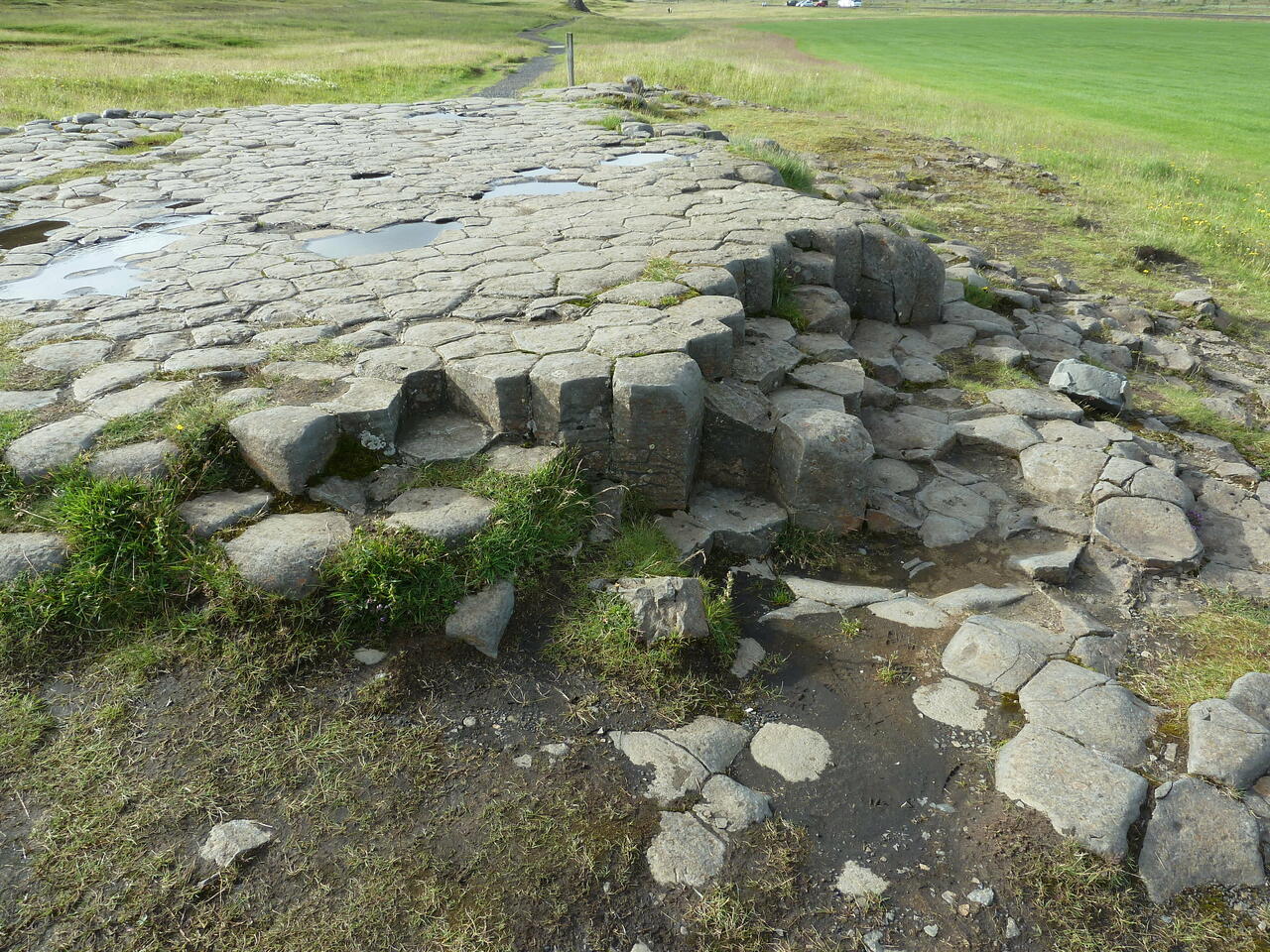 Basaltsäulen am Kirkjugárd; eine Struktur aus mehreckigen Formen, die an eine Pflasterung erinnert; (c) Stephan Matthiesen 2011