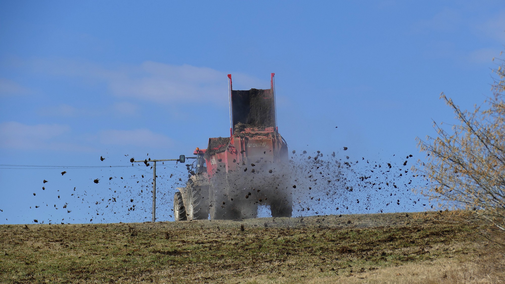 Ein Traktor bringt auf einem Feld Mist aus